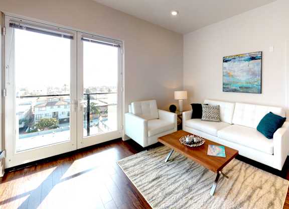 A living room with a white couch and a painting on the wall.