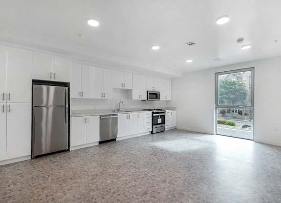 A kitchen with white cabinets and a tiled floor.