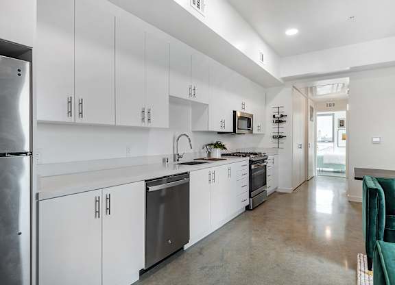 A modern kitchen with white cabinets and a green couch.