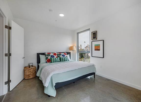 A bedroom with a bed, pillows, and pictures on the wall.