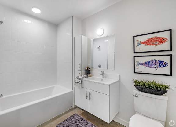 A white bathroom with a white tub, sink, and toilet.