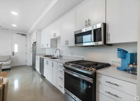 A modern kitchen with white cabinets and stainless steel appliances.