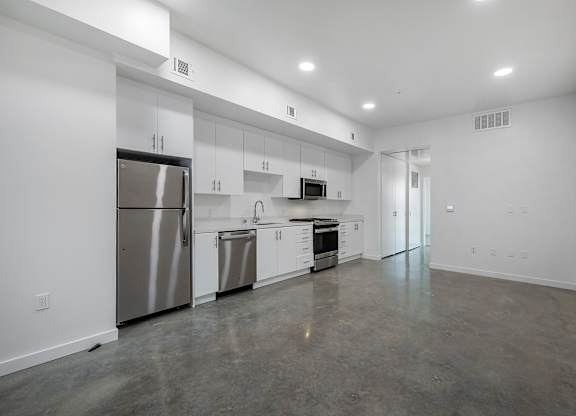 A spacious kitchen with stainless steel appliances and white cabinets.