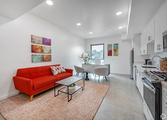A red couch sits in a living room with a glass table and chairs.