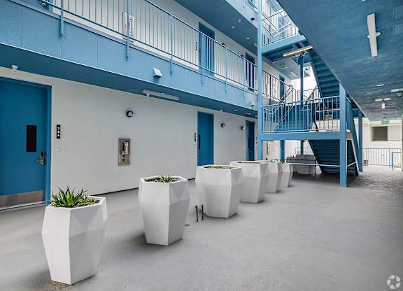 A hallway with blue doors and white planters.