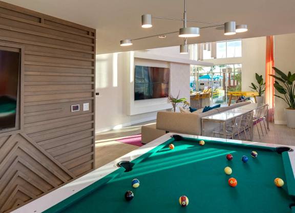A pool table in a room with a wooden wall and a TV.