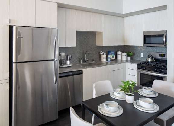 A modern kitchen with a stainless steel refrigerator and a dining table set for two.