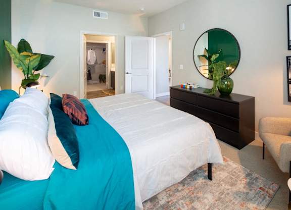 A bedroom with a large bed and a mirror on the wall.