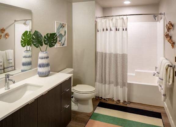 A bathroom with a white sink, toilet, and shower curtain.