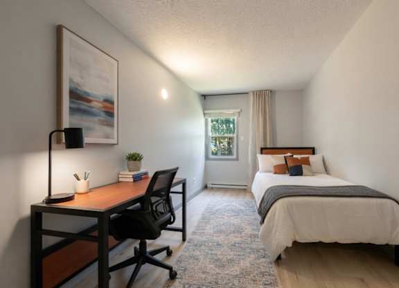 A bedroom with a bed, desk, and chair.