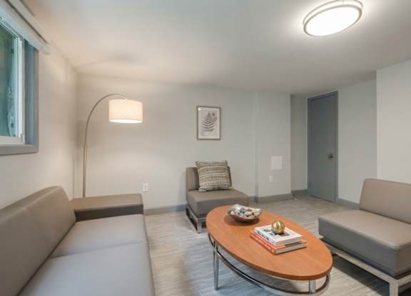 A living room with a grey couch, a wooden coffee table, and a lamp.