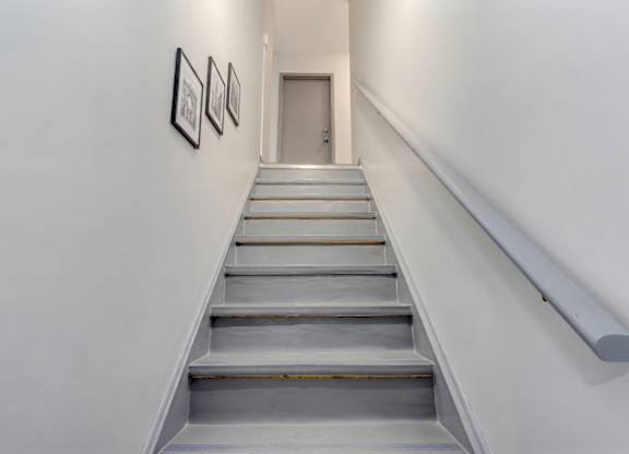 A staircase with a metal handrail and three pictures on the wall.