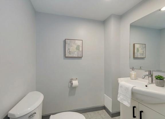 A bathroom with a toilet, sink, and mirror.