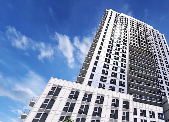A tall building with many windows stands under a blue sky.