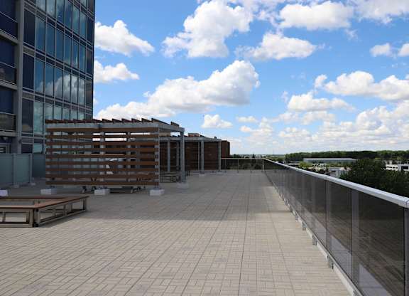 A rooftop patio with a bench and a railing.