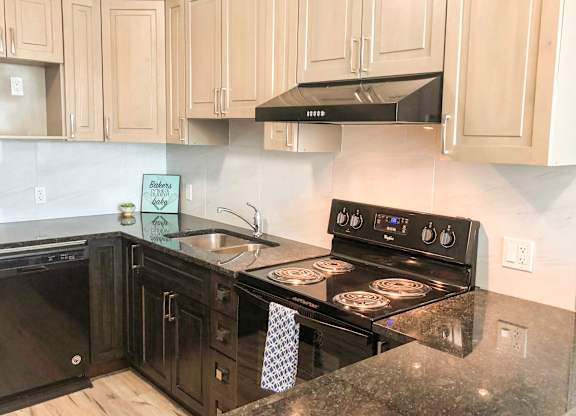 A kitchen with black appliances and wooden cabinets.