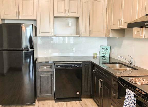 A black fridge and oven in a kitchen with wooden cabinets.