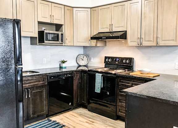 A kitchen with black appliances and wooden cabinets.