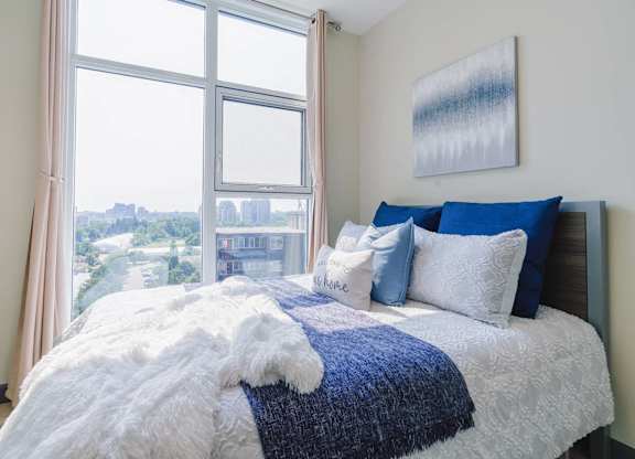 a bedroom with a large window and a bed with blue and white pillows