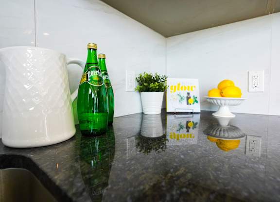 a kitchen counter with a green bottle and a white pitcher on it