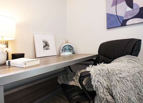 a desk with a lamp and a chair in a room