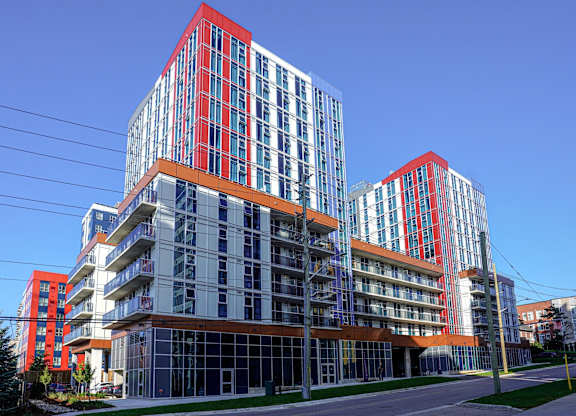 A modern building with red and blue accents stands tall against a clear blue sky.