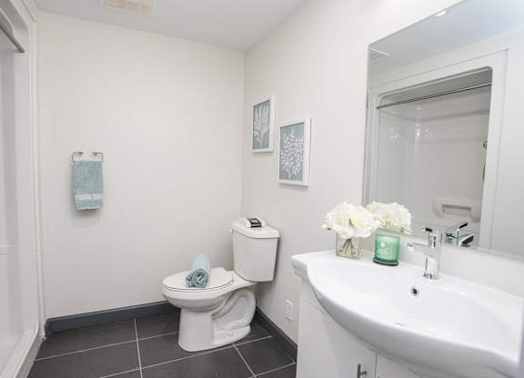 A white toilet with a blue towel on top of it is in a bathroom with a white sink and a mirror.