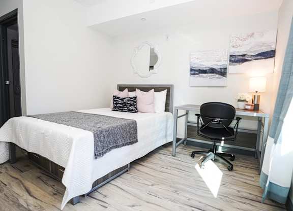 A bedroom with a bed, desk, and chair.