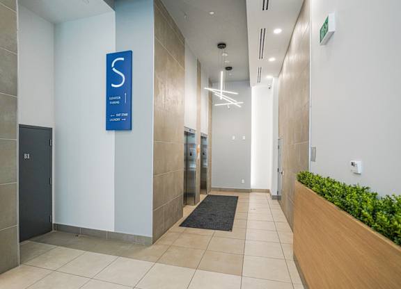 A hallway with a blue sign on the wall and a black mat on the floor.