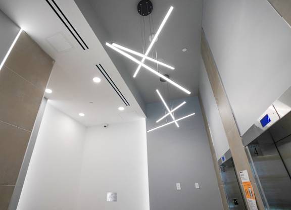 A modern elevator lobby with a white ceiling and a lighting fixture.