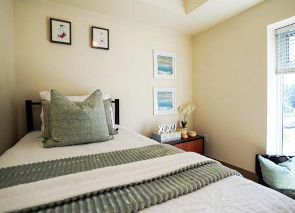 A bed with a striped comforter and a pillow with the word XOXO on it.