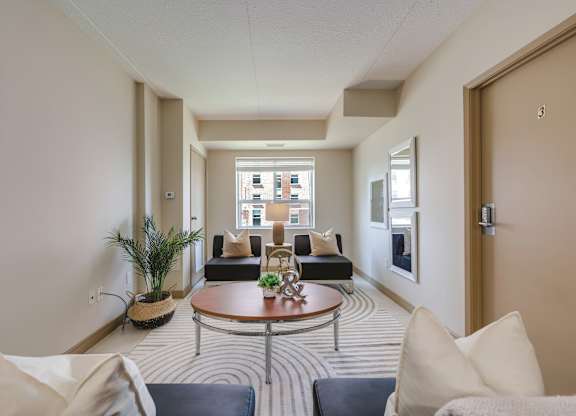 A living room with a striped carpet and a round coffee table.
