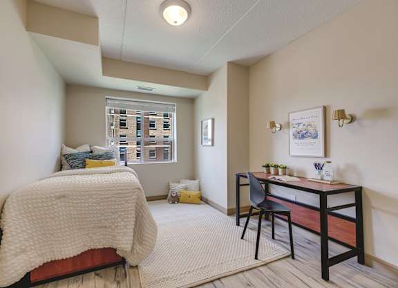 A bedroom with a bed, desk, and chair.