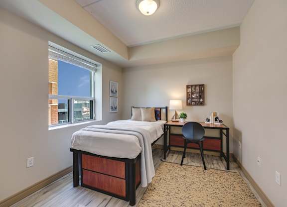 A bedroom with a bed, desk, and chair.