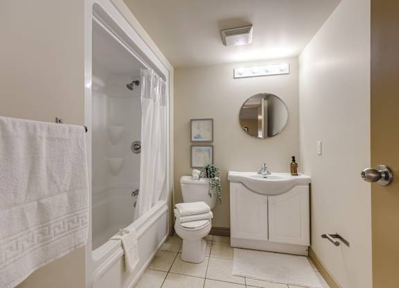 A white towel hangs on a glass shower door in a bathroom.
