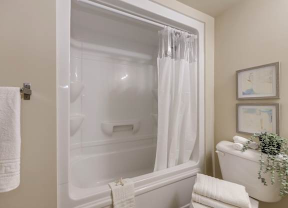 A white bathroom with a white tub and towel.