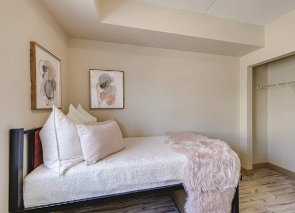 A bedroom with a bed and two framed pictures on the wall.