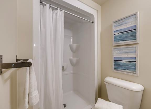 A white bathroom with a towel hanging on a towel rack.