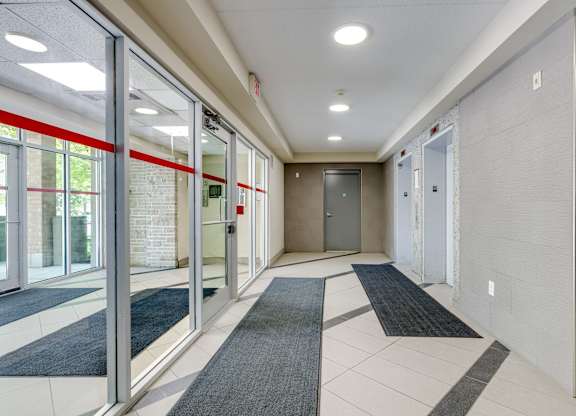 A hallway with a grey carpet and red accents.