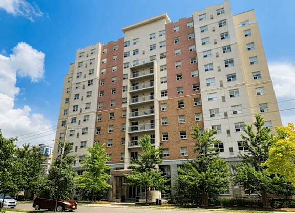 A tall apartment building with a red car parked in front.