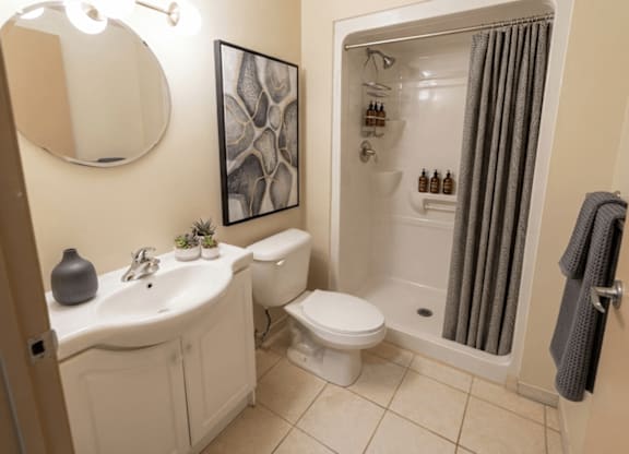 A bathroom with a white sink, toilet, and a shower with a grey curtain.