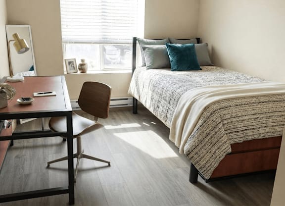 A bedroom with a bed, desk, and chair.