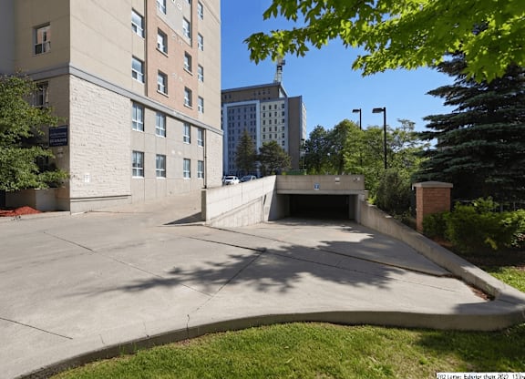 A parking lot in front of a building with a tall tree on the right.
