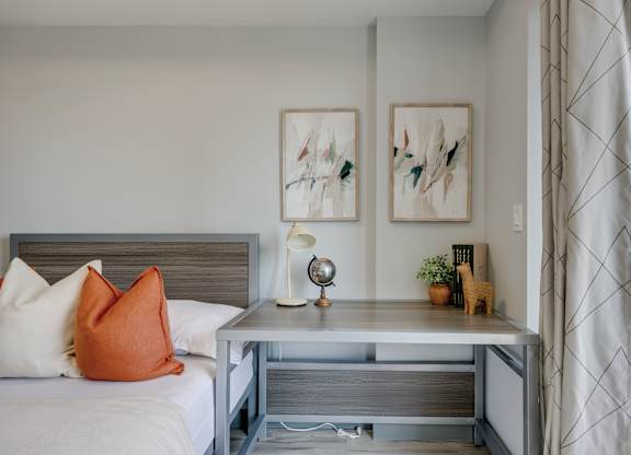 A bedroom with a bed, nightstand, and two framed pictures on the wall.