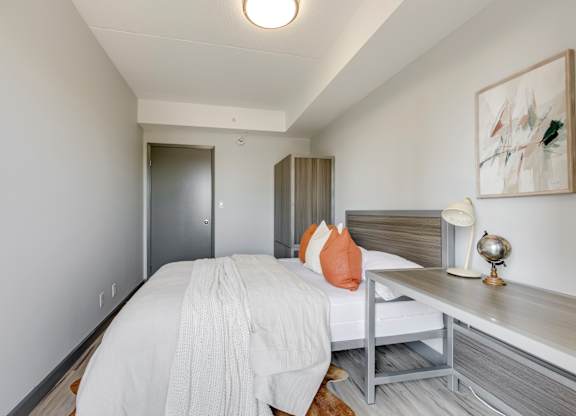 A bedroom with a bed, nightstand, and a painting on the wall.