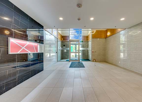 A hallway with a glass wall and a red sign on it.