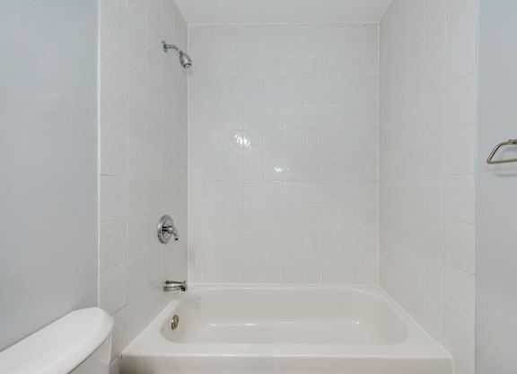 A white bathroom with a tub and toilet.