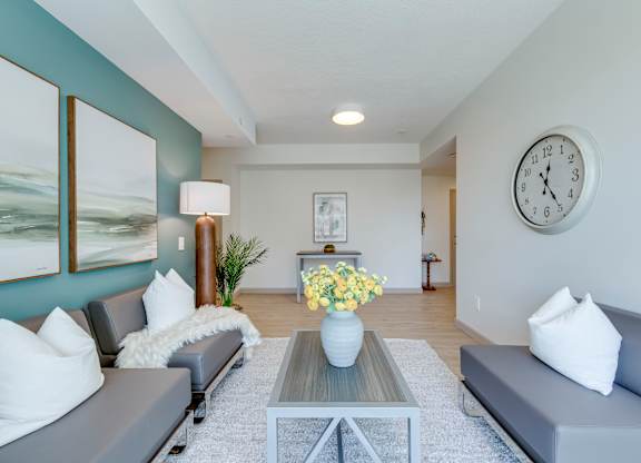A living room with grey couches, a coffee table, and a large painting on the wall.