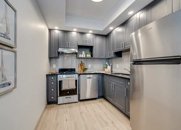 A modern kitchen with stainless steel appliances and wooden flooring.