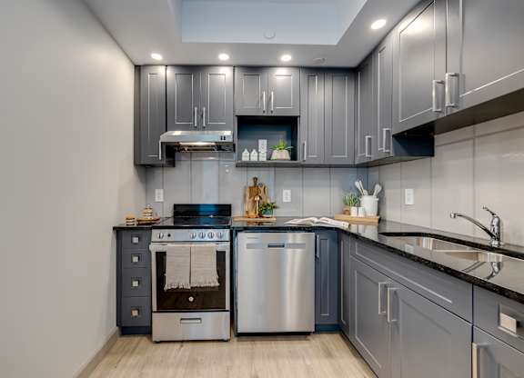A modern kitchen with stainless steel appliances and grey cabinets.